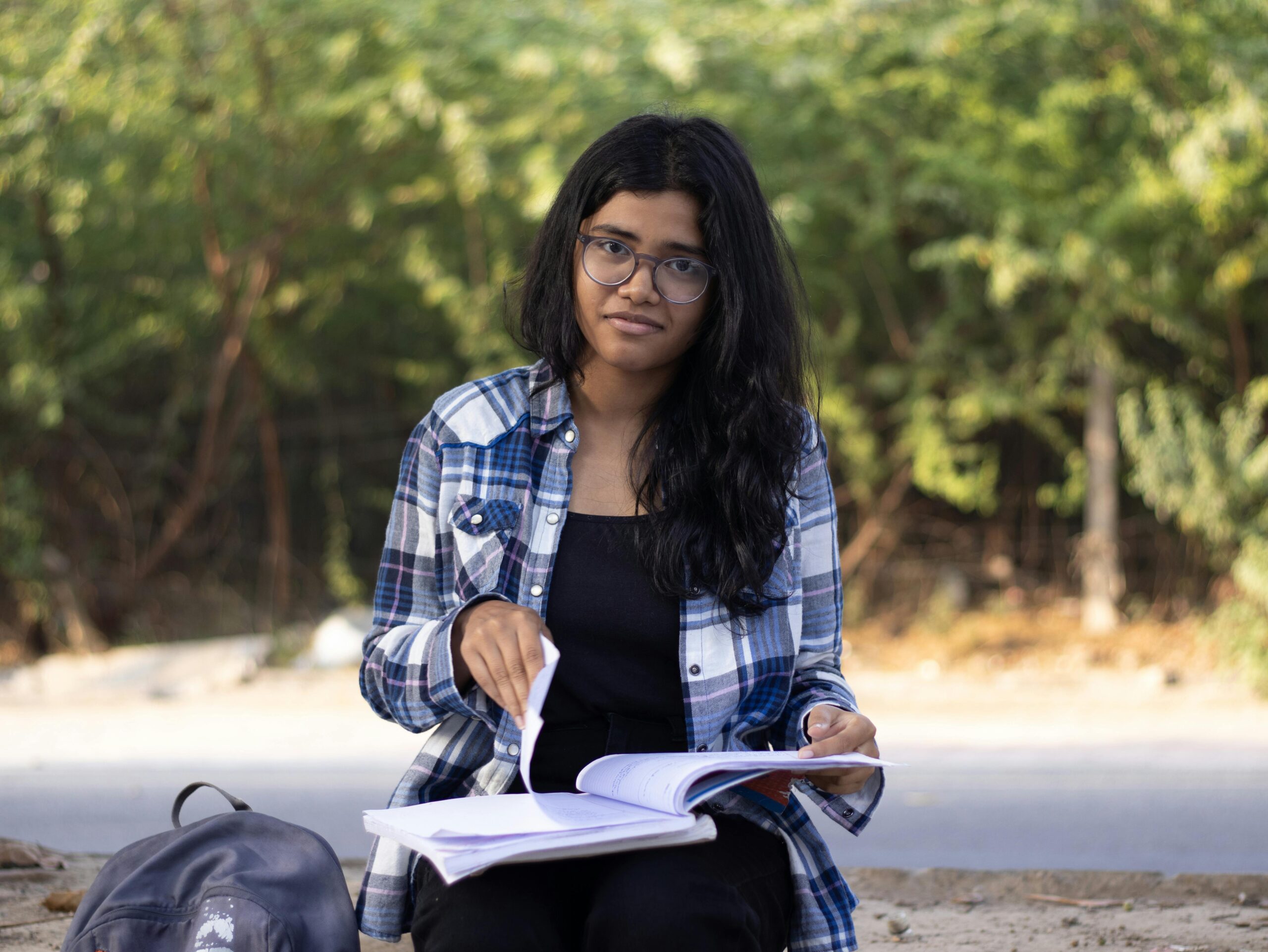Home A young woman studies outdoors in a park in Delhi, enjoying a sunny day.